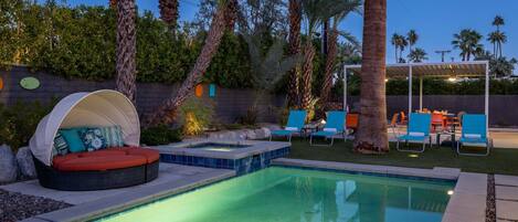 A swimming pool with lounge chairs and a covered seating area.
