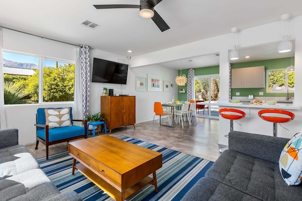 Un salon moderne comprenant un canapé, une table basse, un téléviseur et un coin repas avec des chaises et une table.
