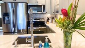Une cuisine moderne dotée d’appareils électroménagers en acier inoxydable, d’un système de filtration de l’eau et d’une plante décorative.