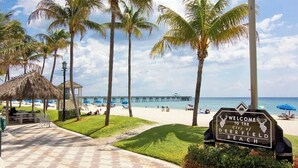 A beachside walkway with a sign welcoming to Deerfield Beach, palm trees, and a pier in the background. - Hemingway 3 Bedroom Condo 2 Blocks from the Beach (Deerfield Beach)