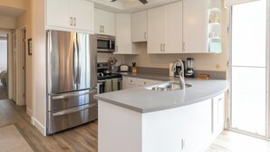 Een moderne keuken met witte kasten, roestvrijstalen apparatuur en een centraal eiland.