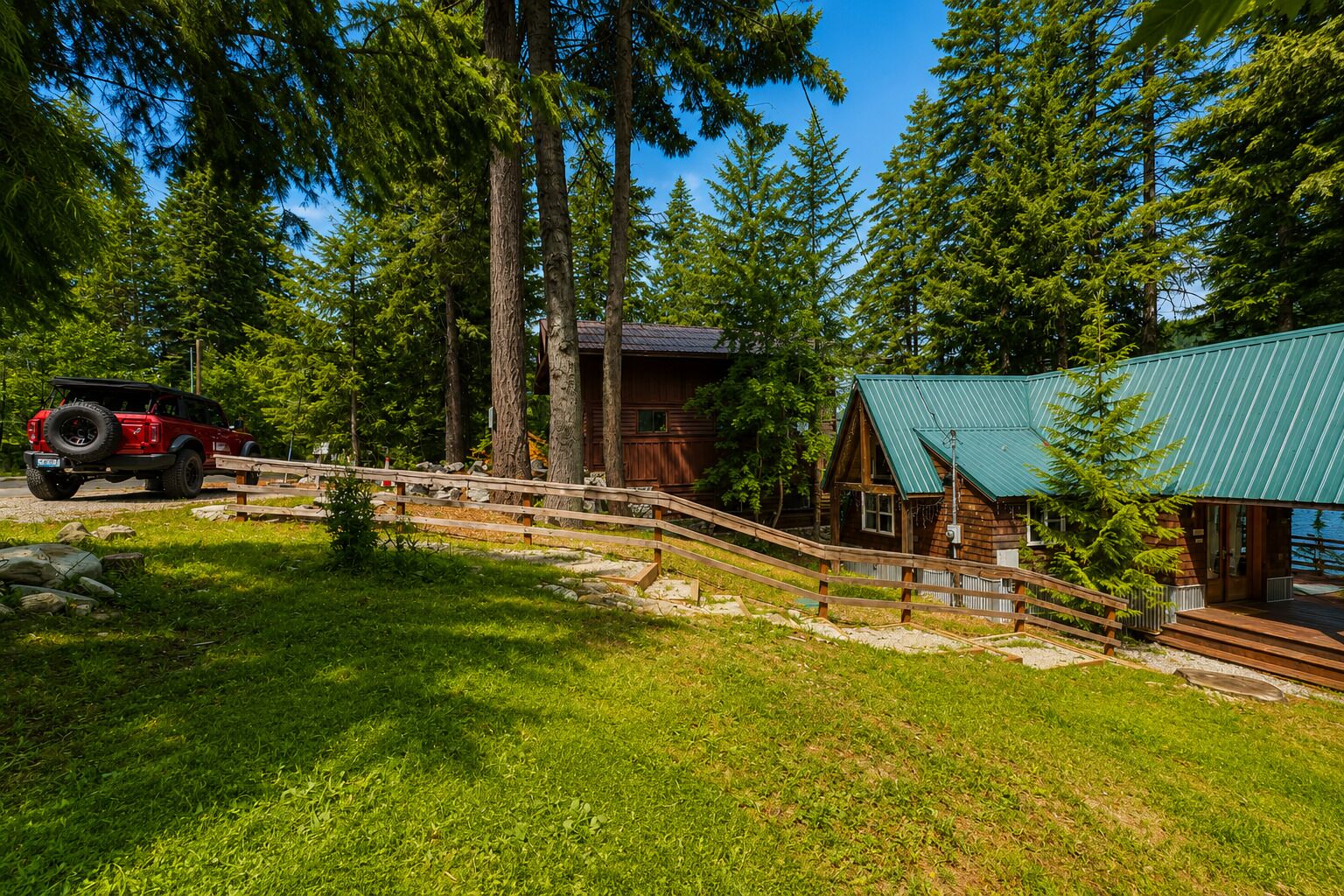 A cabin with a metal roof, surrounded by tall trees and a wooden deck.