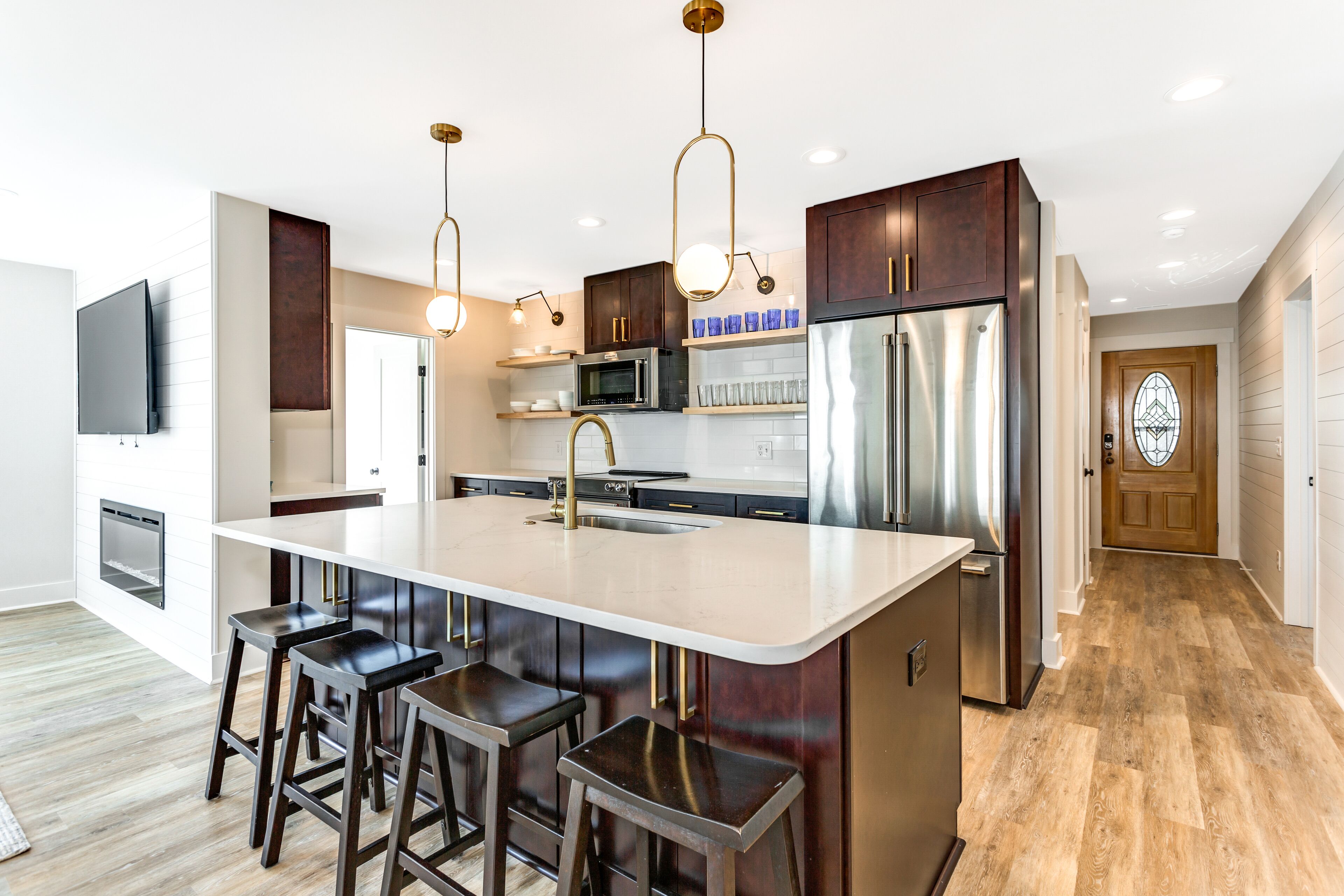A modern kitchen with a central island, stainless steel appliances, and dark wood cabinets.