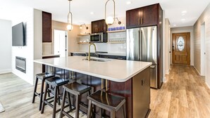 Una cocina moderna con una isla central, electrodomésticos de acero inoxidable y armarios de madera oscura.
