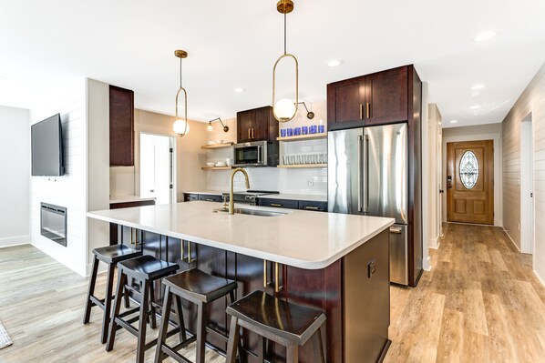 A modern kitchen with a central island, stainless steel appliances, and dark wood cabinets.
