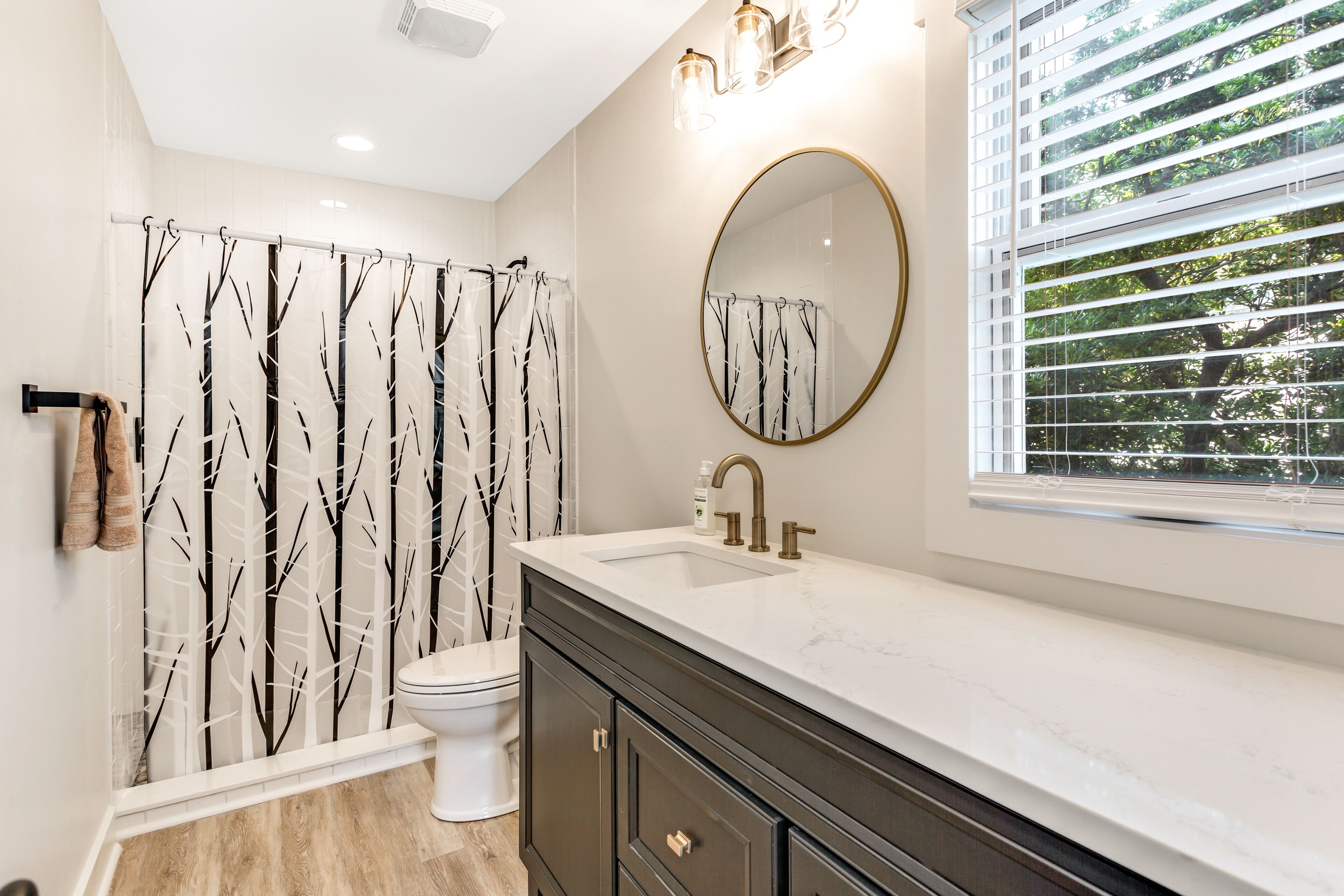 A bathroom with a shower curtain, toilet, sink, and vanity.