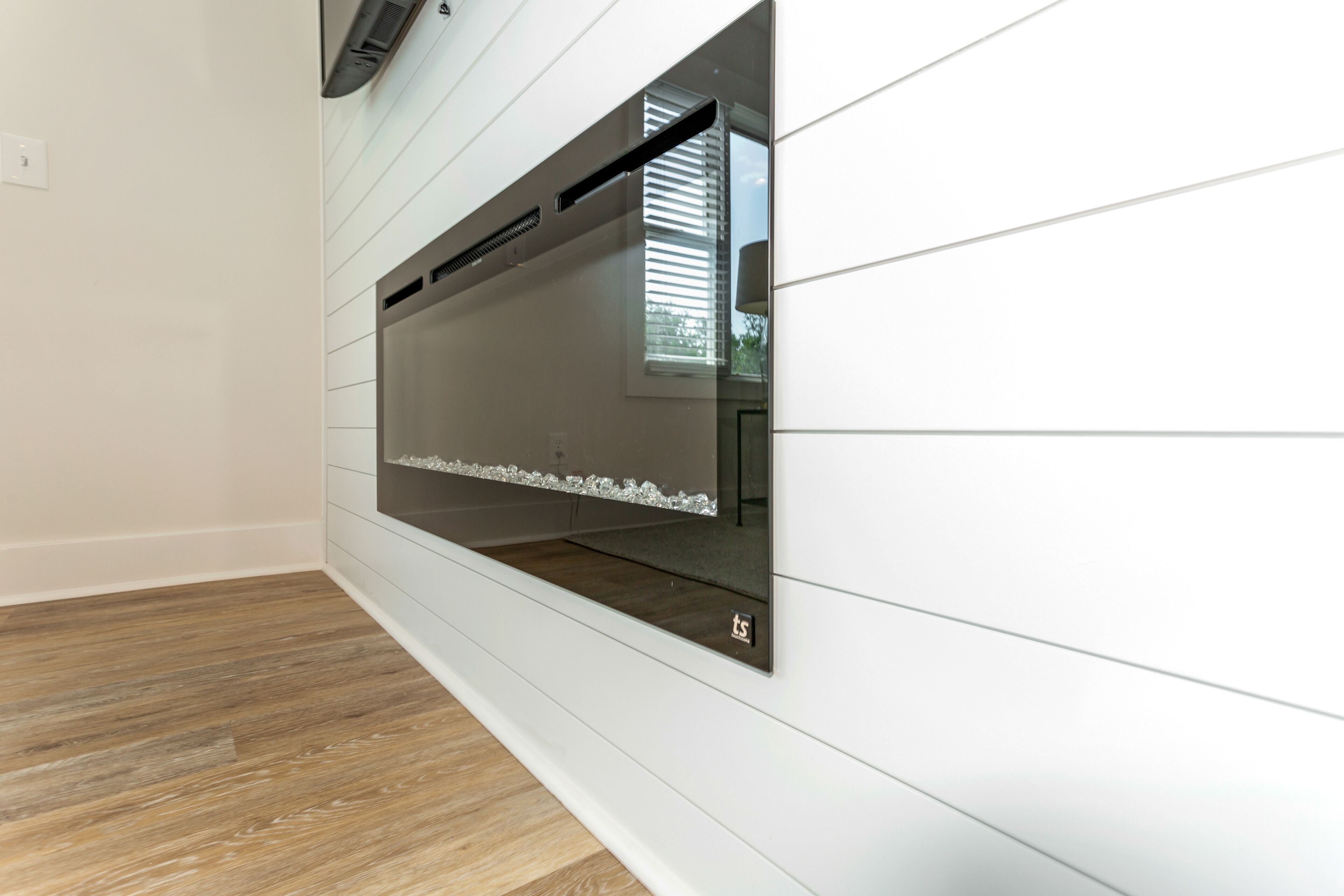 A modern kitchen with a built-in oven and a window with blinds.