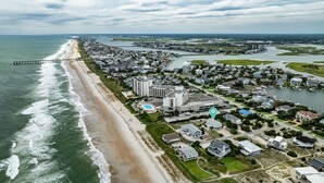 Vue aérienne d’une ville côtière avec une plage, des quartiers résidentiels et un port de plaisance.