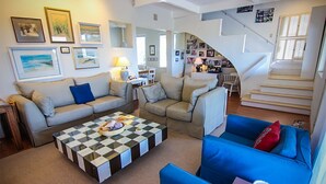 A spacious living room with a checkered coffee table, two sofas, and a staircase leading to another level.