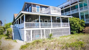 A coastal building with a balcony, a staircase, and a view of the beach.