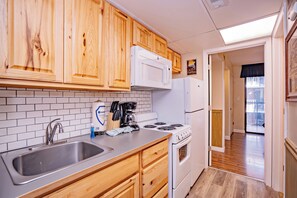 A kitchen with wooden cabinets, a stainless steel sink, a stove, and a refrigerator.