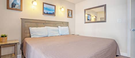 Habitación de hotel con una cama grande, una mesita de noche con una planta y lámparas fijadas a la pared.