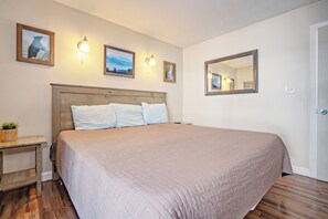 A hotel room with a large bed, a bedside table with a plant, and wall-mounted light fixtures. - Oak Square 211 is a lovely condo with private balcony overlooks pool in downtown (Gatlinburg)
