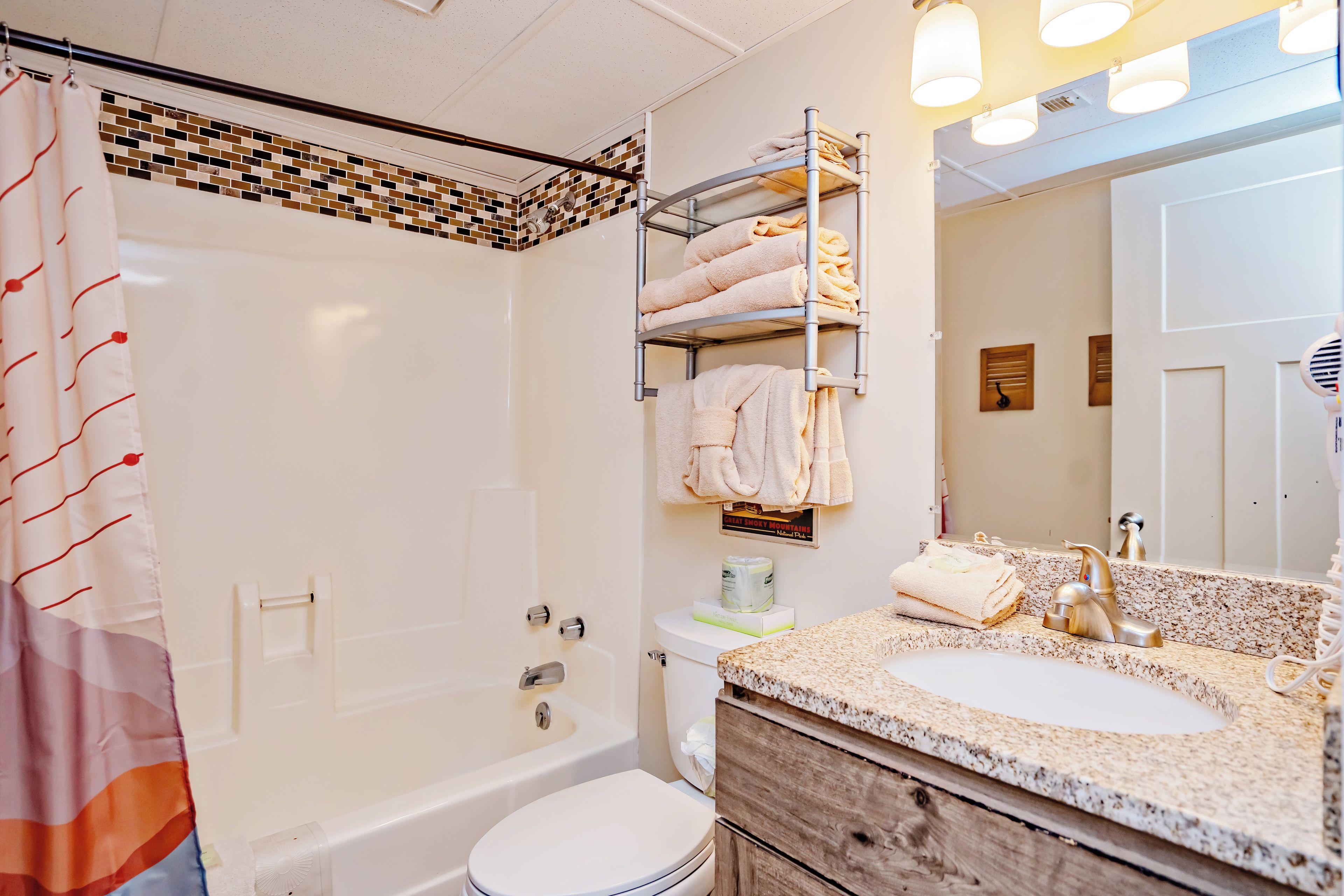 A bathroom with a bathtub, toilet, and a vanity with a sink and mirror.