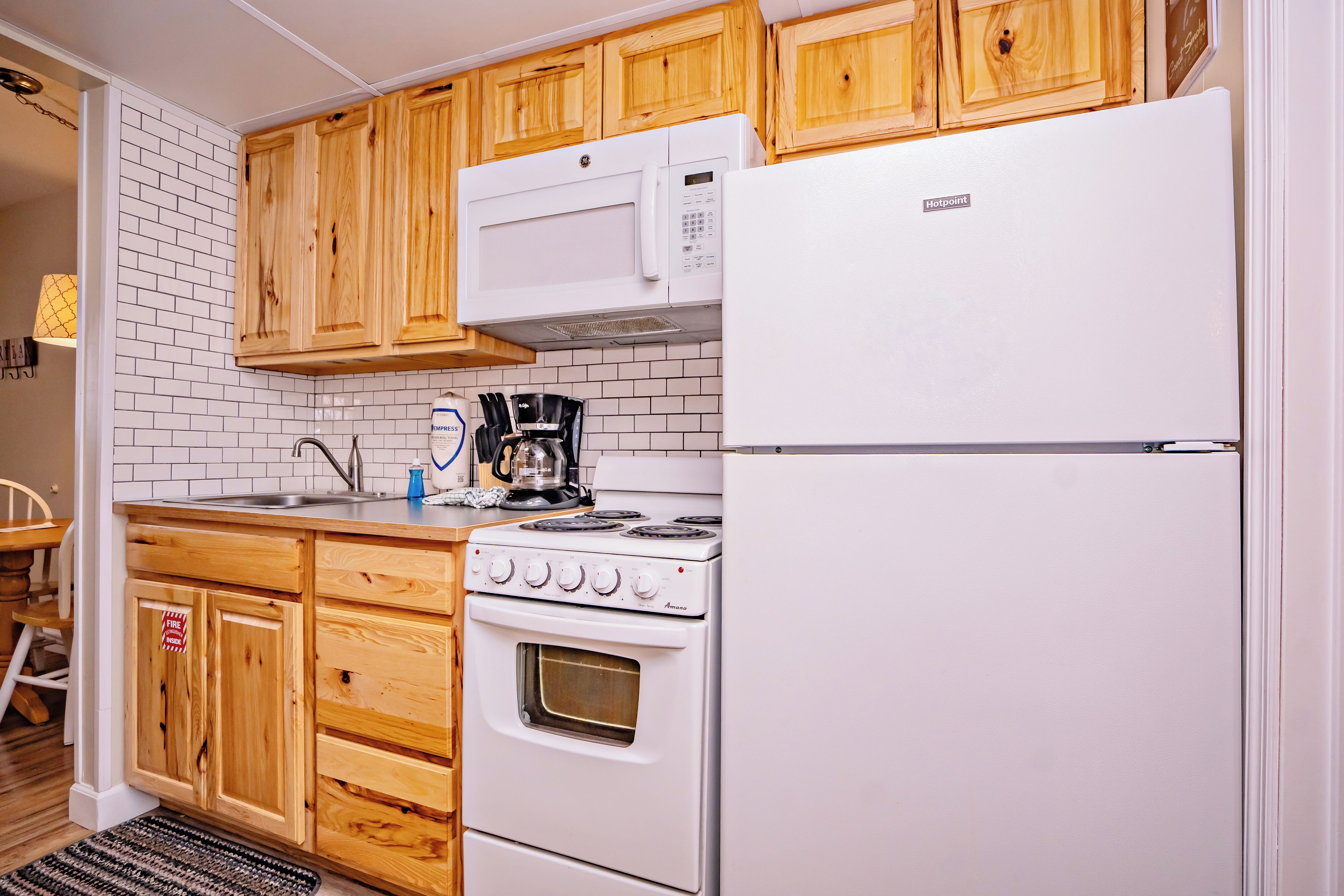 Une cuisine de taille réduite, avec des meubles en bois, un réfrigérateur blanc, une cuisinière et un four à micro-ondes.