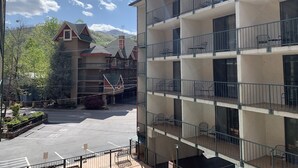 A multi-story hotel with balconies, a parking lot, and a view of a mountain.