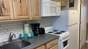 A kitchen with wooden cabinets, a white microwave, a stove, and a refrigerator.