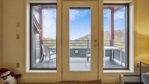 A room with a large sliding glass door leading to an outdoor deck with a view of a forested hillside. - Gorgeous views, tastefully decorated Ski on/ski off 3 bedroom condo, Lodges 303 (Killington)