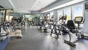 A gym with various exercise machines, large windows, and a mirrored wall. - Gorgeous views, tastefully decorated Ski on/ski off 3 bedroom condo, Lodges 303 (Killington)