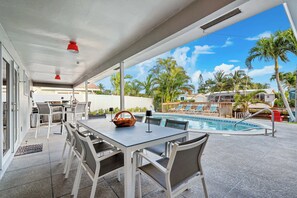 A covered outdoor area with a pool, dining table, and chairs. - Coral Ridge Isles Beauty - Waterfront Pool Villa, BBQ (Fort Lauderdale)