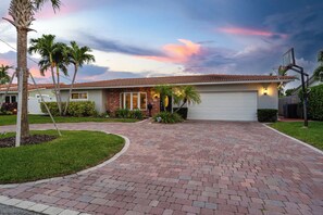 A residential house with a brick driveway, palm trees, and a garage. - Coral Ridge Isles Beauty - Waterfront Pool Villa, BBQ (Fort Lauderdale)