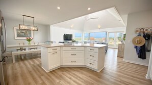 A spacious kitchen with a large island, wooden flooring, and a view to the outside. - Wrightsville Beach Coastal Retreat (Wrightsville Beach)