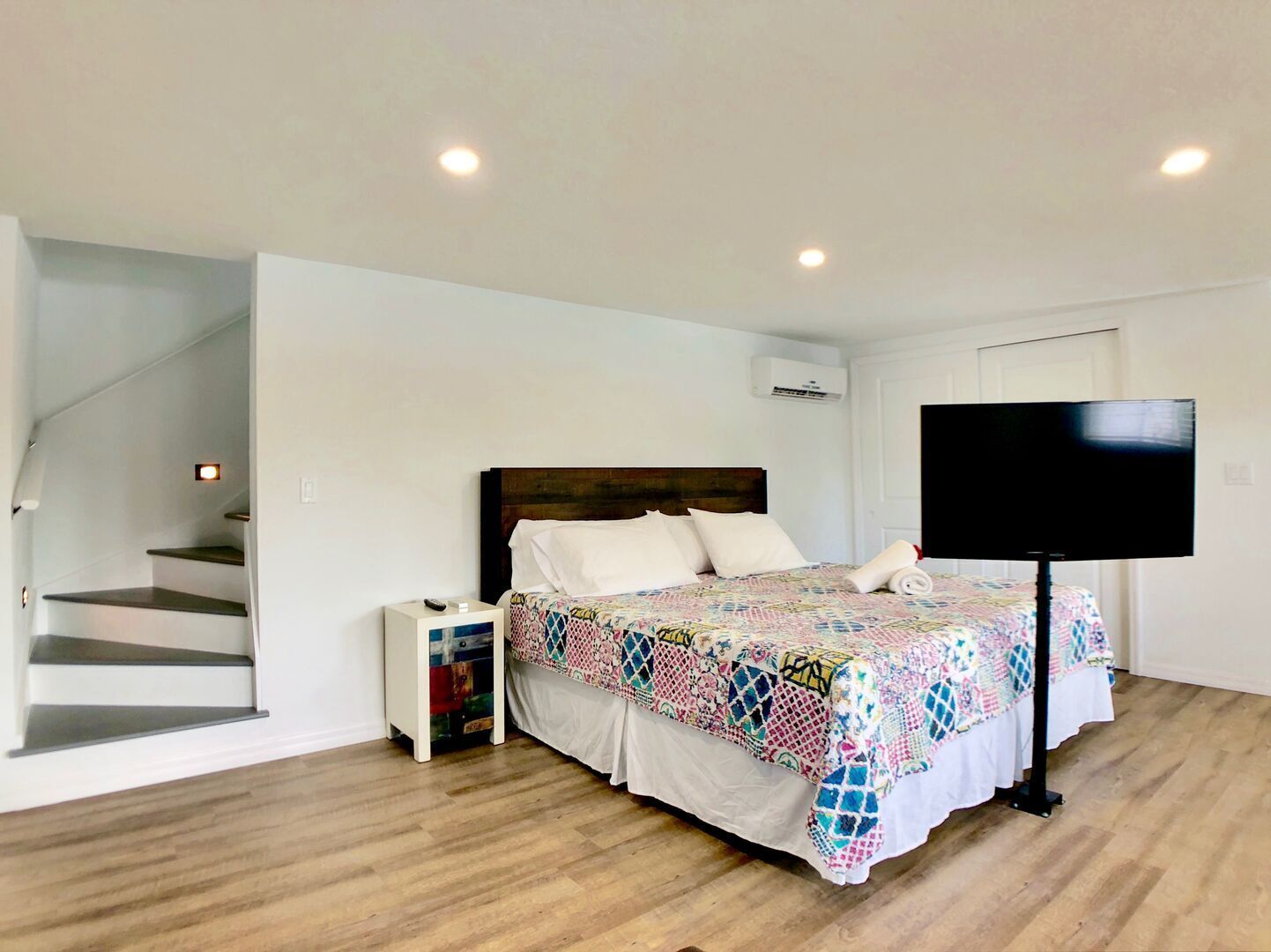 Ein Schlafzimmer mit Bett, Fernseher und Treppe.