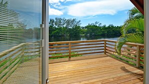 A wooden deck with a railing overlooking a lake, surrounded by lush greenery.