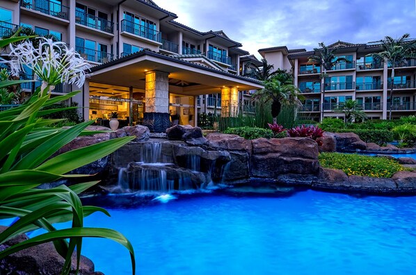 Un hotel con piscina, cascada y una zona cubierta con plantas.