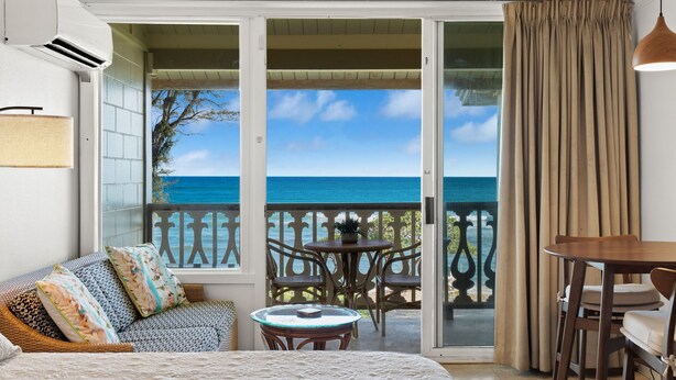 Un balcone con vista sull'oceano, arredato con un divano, sedie e un tavolo.