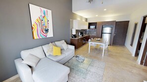 Un salon moderne avec un canapé gris, une table basse en verre et un tableau abstrait aux couleurs vives accroché au mur.