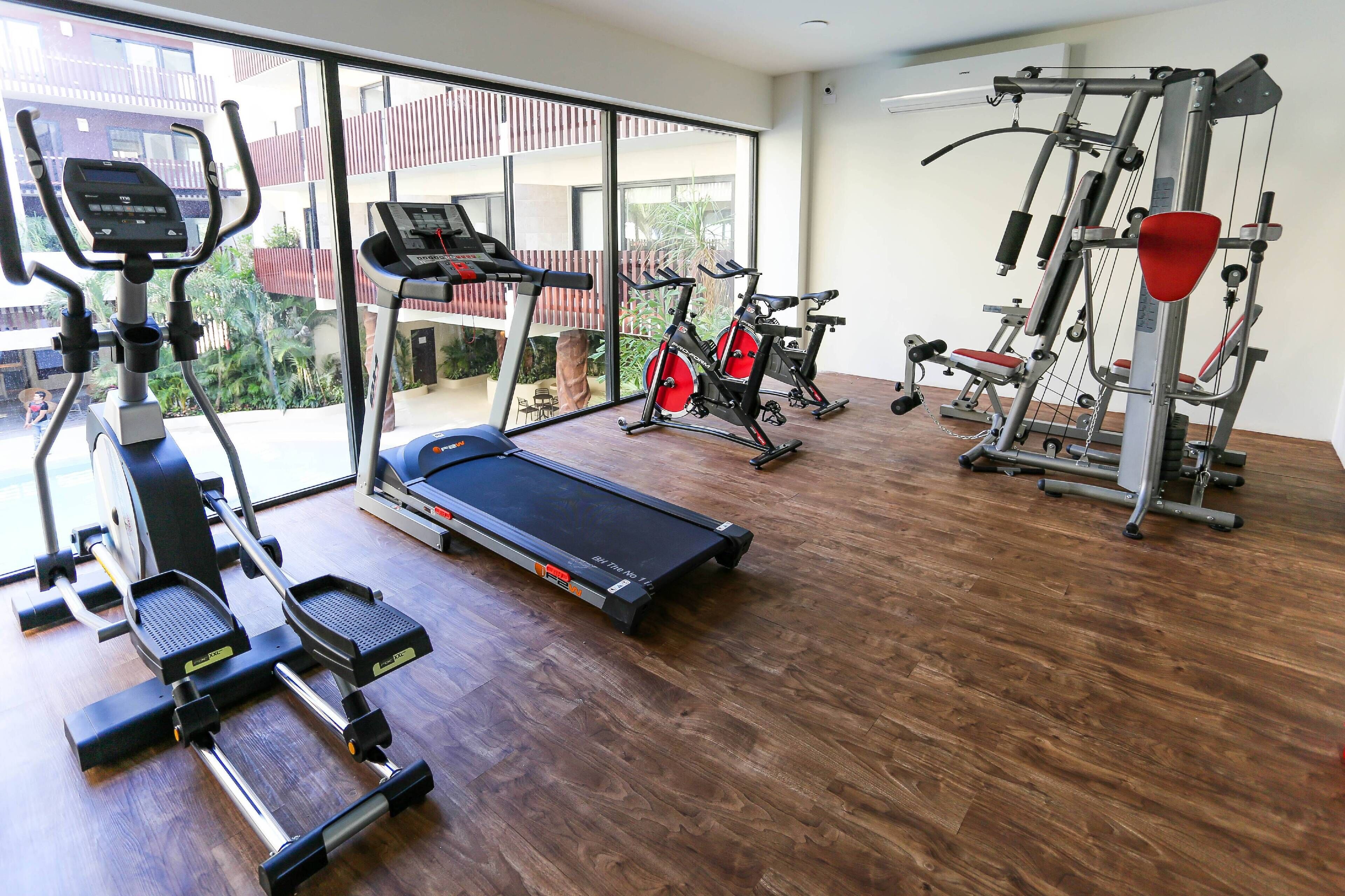 A gym with cardio machines, weight equipment, and a treadmill.