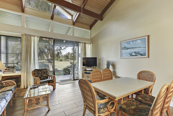 A dining area with a table and chairs, a television, and a window with curtains.