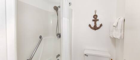Een badkamer met een bad, toilet en douche.