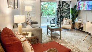 Ein Wohnzimmer mit einer Couch, einem Couchtisch, einem Fernseher und einem Deckenventilator.
