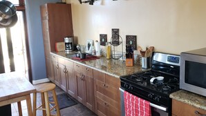 A kitchen with wooden cabinets, a gas stove, a microwave, and various kitchen utensils. - Large Custom Guest House On Hill Top Estate In Bonsall (Bonsall)