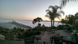 An outdoor seating area with tables and chairs, overlooking a mountainous landscape and a sea of clouds. - Large Custom Guest House On Hill Top Estate In Bonsall (Bonsall)