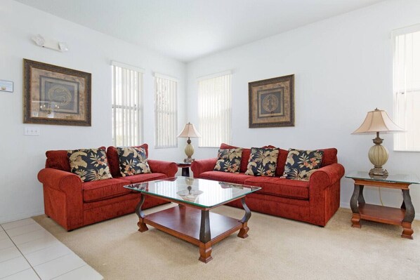 A room with two red sofas, a glass coffee table, and two lamps. - Palm Breeze: Private Pool/Spa & 24/7 Support! (Davenport)