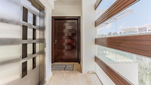 Un pasillo moderno con una puerta de madera, un balcón de vidrio y vistas al exterior.