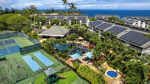 Een resort met verschillende tennisbanen, een zwembadgedeelte en zonnepanelen op de daken.