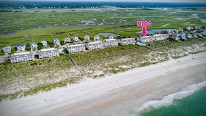 Un hôtel en bord de mer, composé de plusieurs bâtiments, avec une plage et un terrain de golf en arrière-plan.