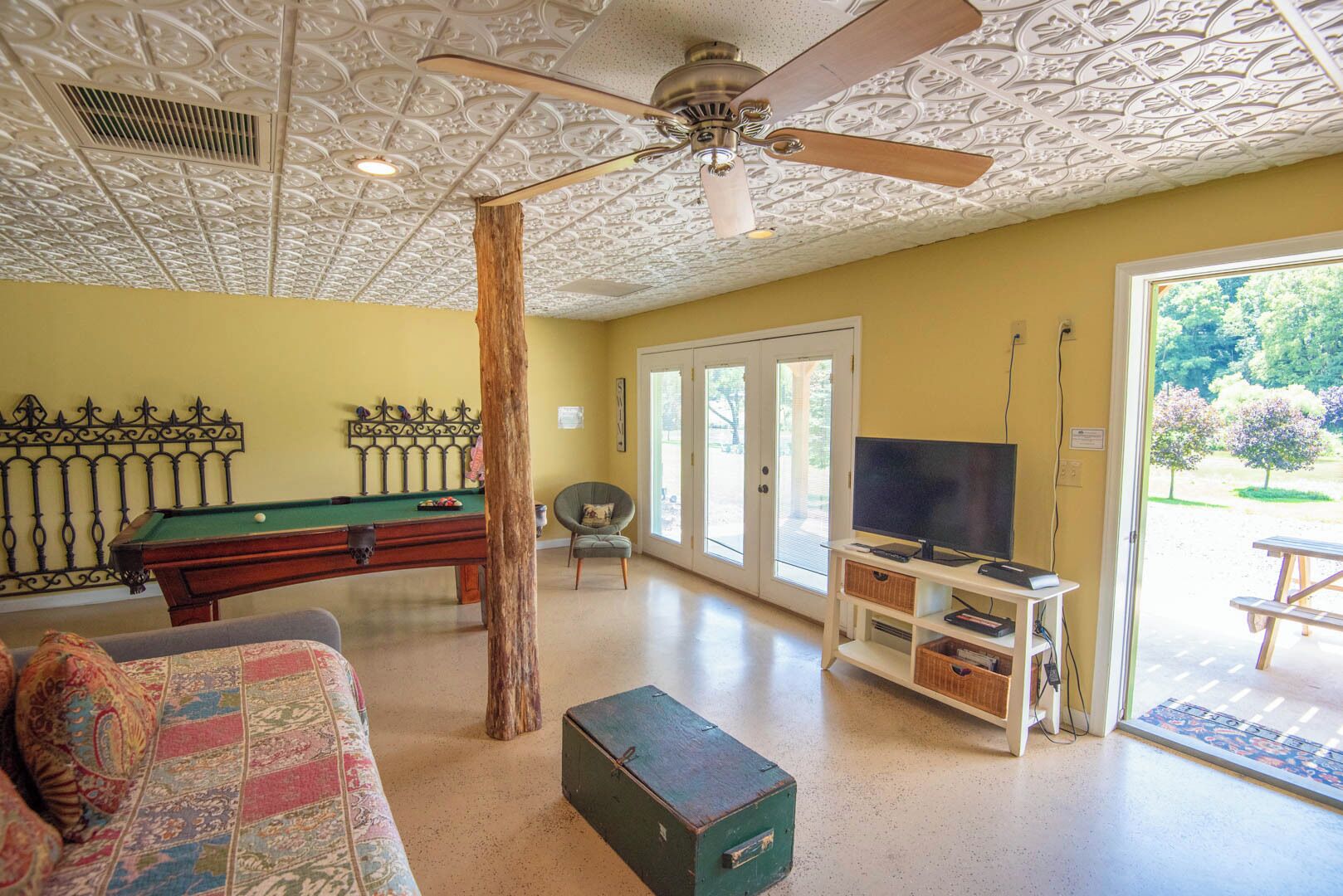 A room with a pool table, a television, and a ceiling fan.