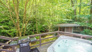A hot tub on a wooden deck surrounded by lush greenery. - Creekside Escape | Hot Tub & Wooded Privacy | Prime West Jefferson Location (West Jefferson)