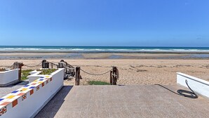 A beach view with a concrete walkway leading to the shore, a rope barrier, and a tiled wall with a geometric pattern. - Buenos Tiempos – Beachfront, Sleeps 6, Rocky Point (Puerto Peñasco)