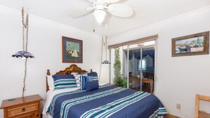 A bedroom with a large bed, a wooden nightstand, a ceiling fan, and a window with a view of boats. - Buenos Tiempos – Beachfront, Sleeps 6, Rocky Point (Puerto Peñasco)