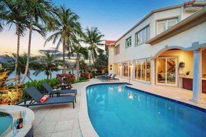 A poolside area with lounge chairs, a hot tub, and a view of a building with large windows and a pool. - Delray Beach Intracoastal Elegance Waterfront pool (Delray Beach)