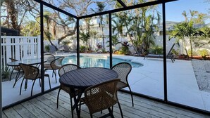 A covered outdoor area with a pool, lounge chairs, and a table with chairs. - Renovated Siesta Key Vacation Rental W/ Heated Pool Walking Distance to Beach (Siesta Key)