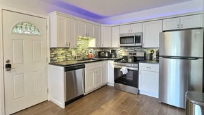 A modern kitchen with white cabinets, stainless steel appliances, and a wooden floor. - Renovated Siesta Key Vacation Rental W/ Heated Pool Walking Distance to Beach (Siesta Key)
