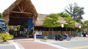 A restaurant with a thatched roof, outdoor seating, and a blue facade. - Renovated condo with easy beach access on Siesta (Siesta Key)
