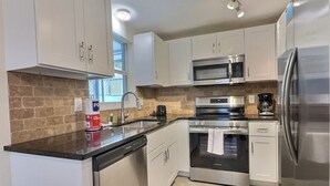 A modern kitchen with white cabinets, a stainless steel refrigerator, a microwave, an oven, and a dishwasher. - Renovated condo with easy beach access on Siesta (Siesta Key)